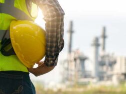 engineering man with white safety helmet standing in front of oil refinery building structure in heavy petrochemical industry